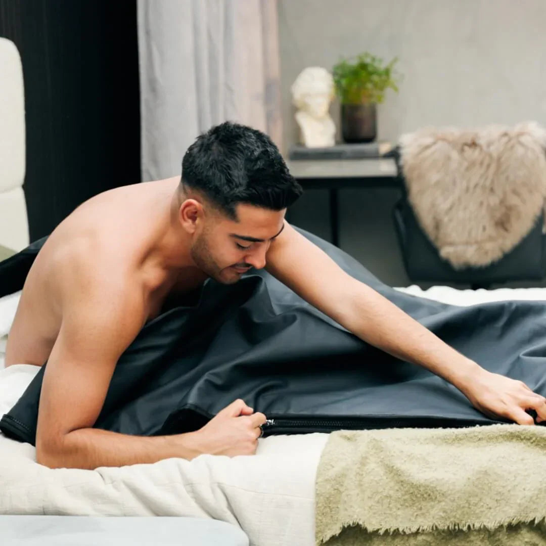 Mann legt sich in die Comforth Infrarot-Saunadecke auf dem Bett